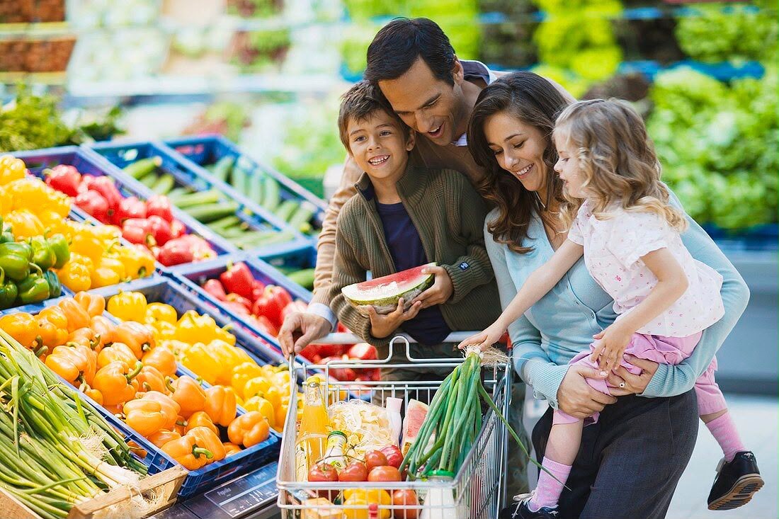 Une famille fait ses courses au rayon fruits et légumes d'un supermarché